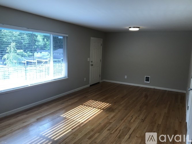 A room with wooden flooring and a window showing an outdoor view.