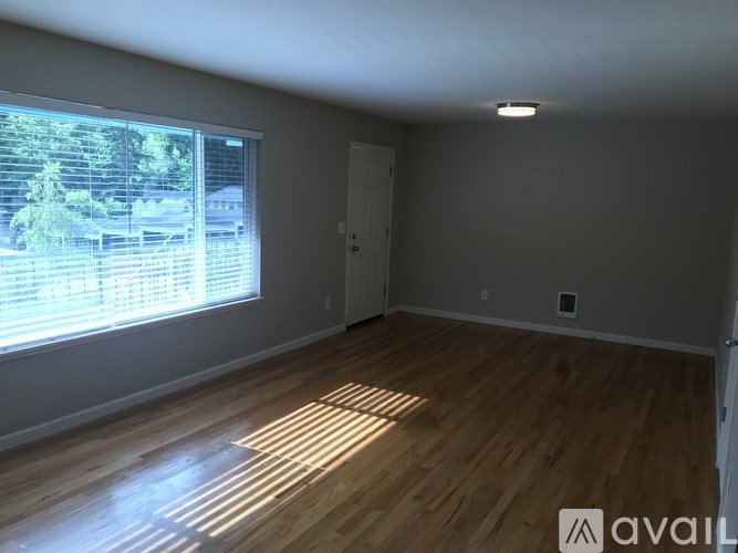 A room with wooden flooring and a window showing an outdoor view.