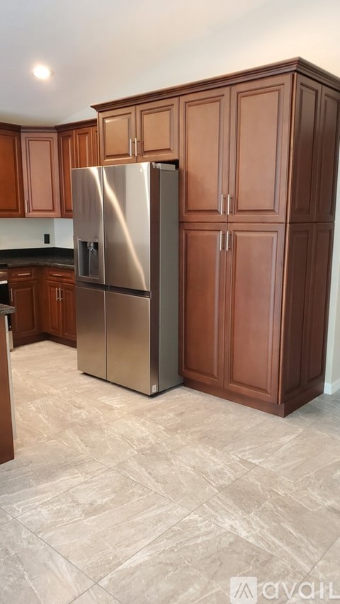 A kitchen with a stainless steel refrigerator and wooden cabinets.