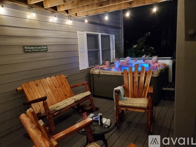 A wooden deck with chairs and a hot tub at night.