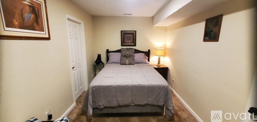A bedroom with a bed, nightstand, and two pictures on the wall.