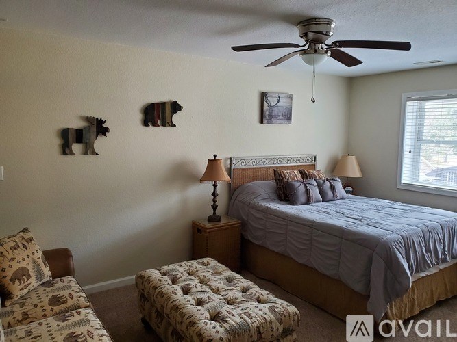 A bedroom with a bed, a bench, and a ceiling fan.