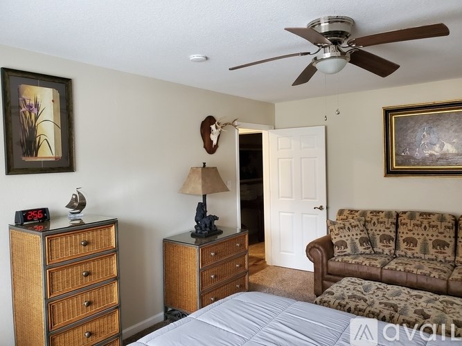 A bedroom with a bed, dresser, and a ceiling fan.