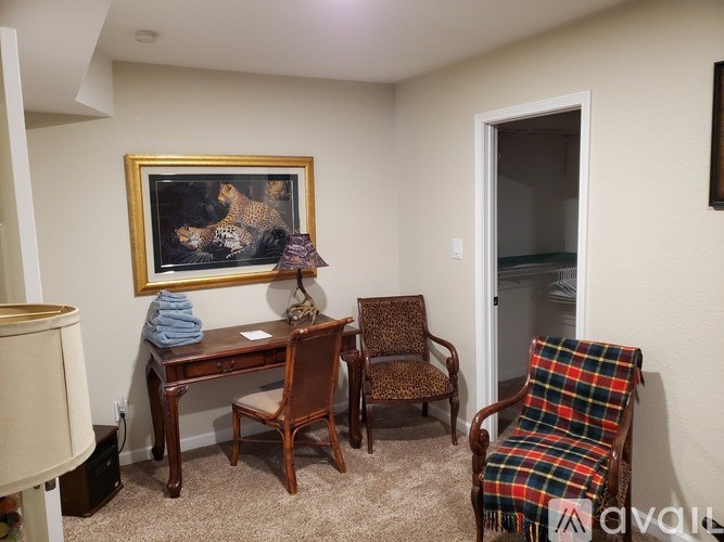 A room with a painting, a desk, a chair, and a cabinet.