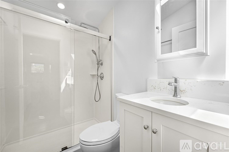 A white bathroom with a toilet, sink, and shower.