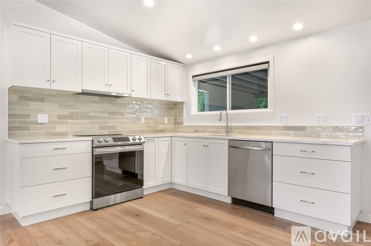 A kitchen with white cabinets and a wooden floor.