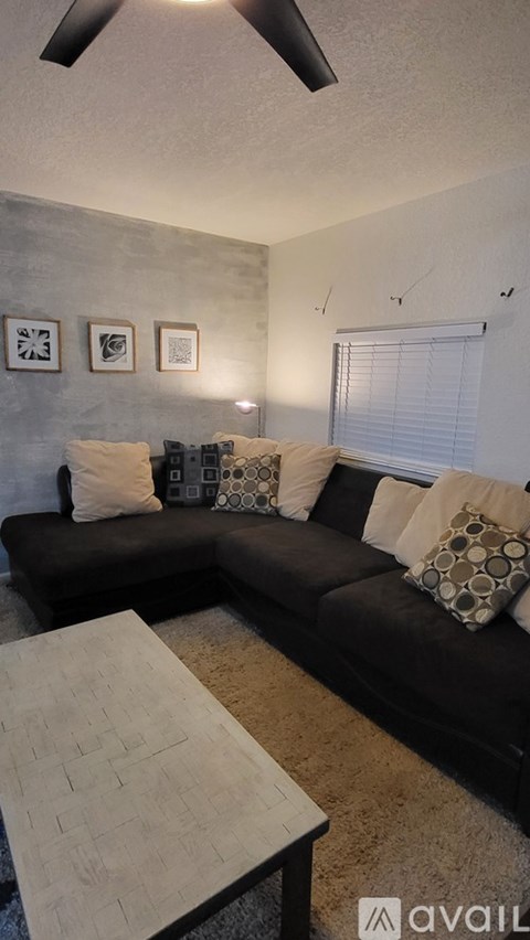 A living room with a black couch and a white coffee table.