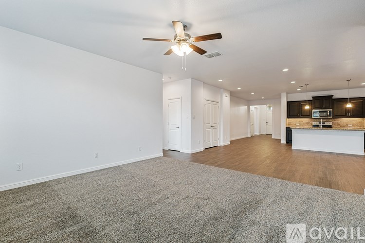A spacious room with a ceiling fan and a carpeted floor.