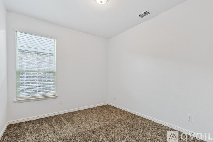 A room with a carpeted floor and a window with blinds.