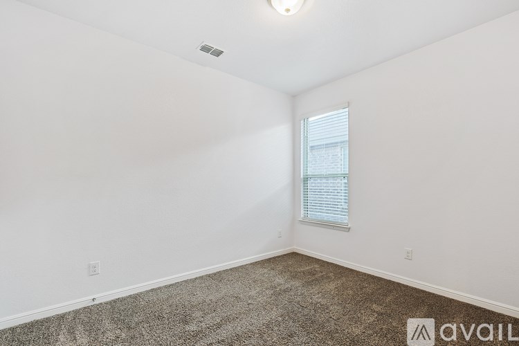 A room with a carpeted floor and a window with blinds.