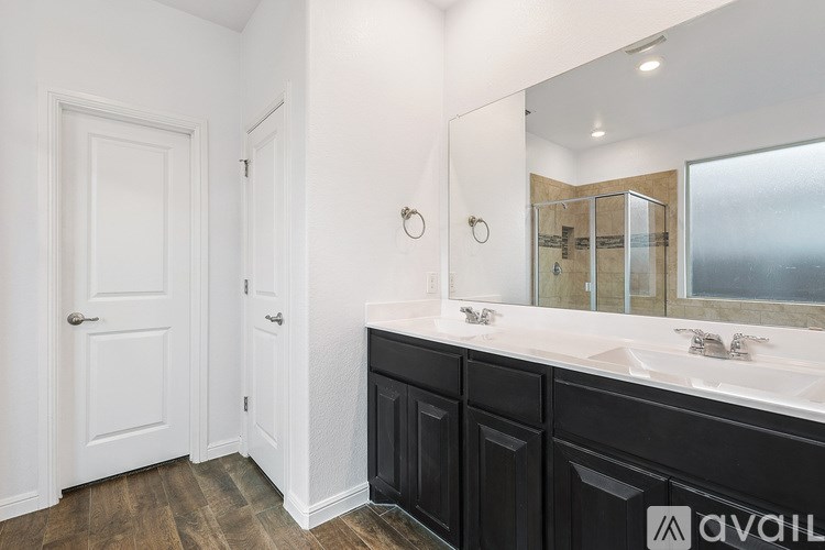 A bathroom with a white door, black cabinetry, and a large mirror.