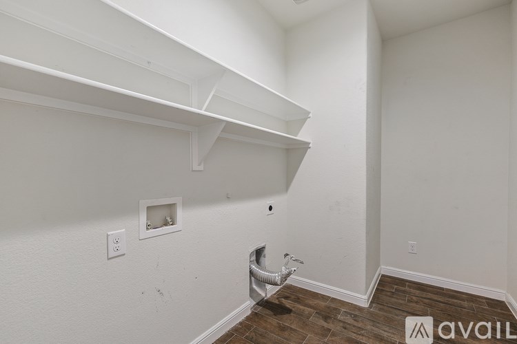 A white wall with a small square mirror and a white shelf above it.