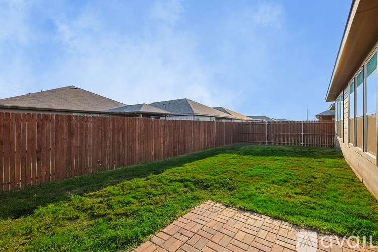 A backyard with a wooden fence and a brick walkway.