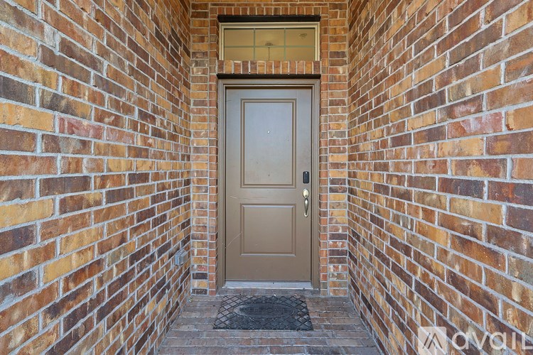 A brown door is at the end of a brick hallway.