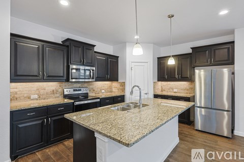 A kitchen with black cabinets and a granite countertop.