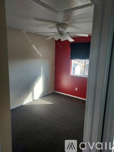 A room with a ceiling fan and a window with blinds.
