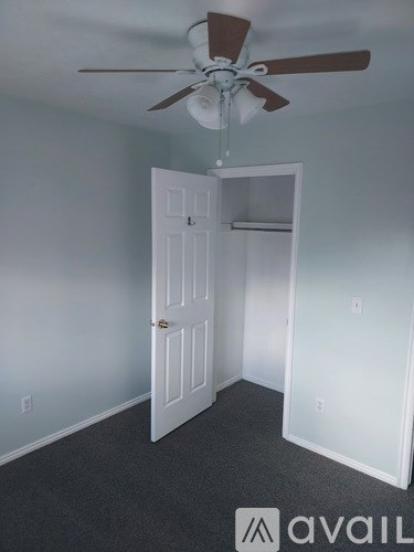 A room with a ceiling fan and a door.