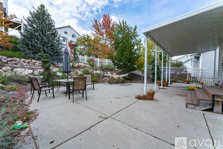 A patio with a table and chairs is surrounded by trees.