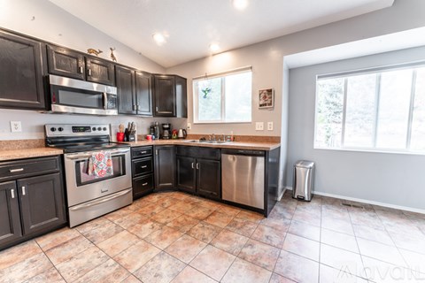 A kitchen with black cabinets and a tile floor.