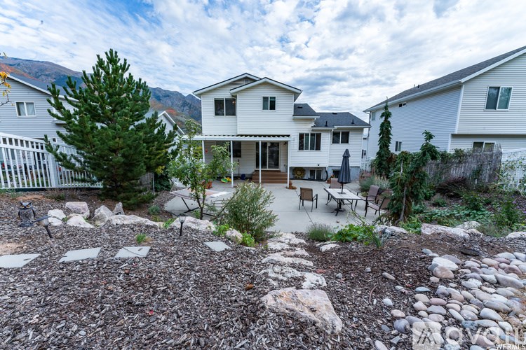 A white house with a rocky front yard and a mountain in the background.