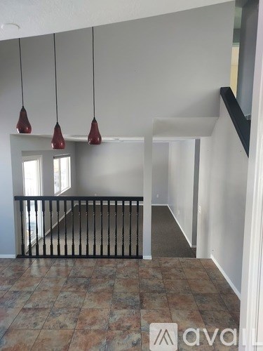 A room with a tiled floor and a staircase with a black railing.