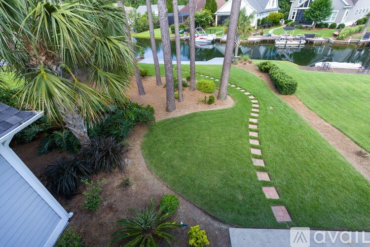 A well-manicured lawn with a pathway and a house in the background.