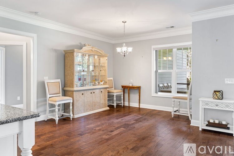 A room with wooden floors and furniture including a chair, a table, and a cabinet.