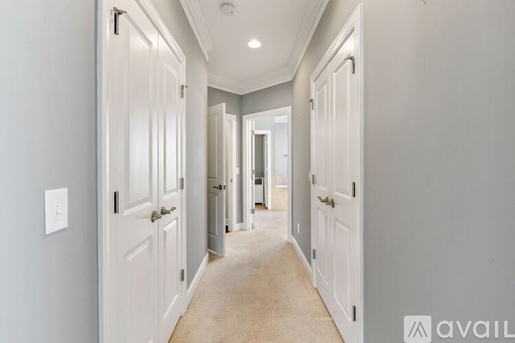 A hallway with white doors and a carpeted floor.
