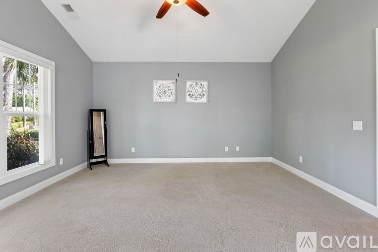 A room with a ceiling fan and two wall art pieces.