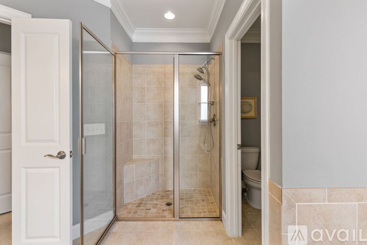 A bathroom with a walk-in shower and a toilet visible through the door.
