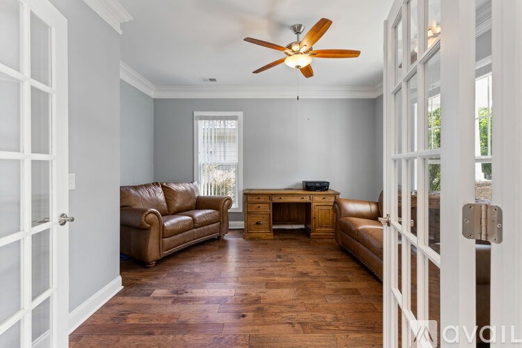 A living room with a brown leather couch and a wooden desk.