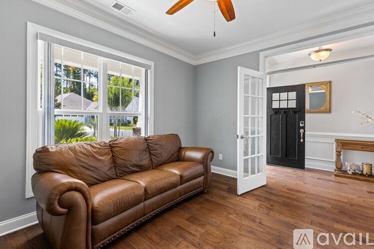 A brown leather couch sits in a room with a window and a fireplace.