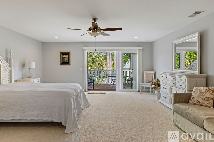 A bedroom with a bed, dresser, and couch with a ceiling fan.