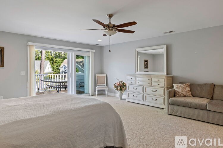 A bedroom with a large bed, a dresser, a couch, and a ceiling fan.