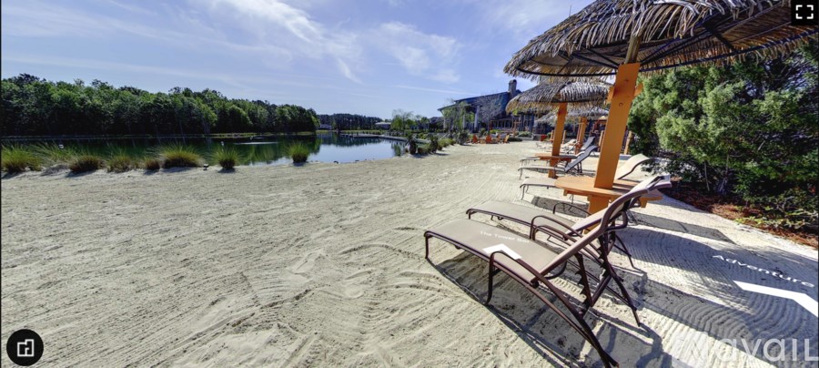 A beach scene with chairs and umbrellas facing a calm body of water.
