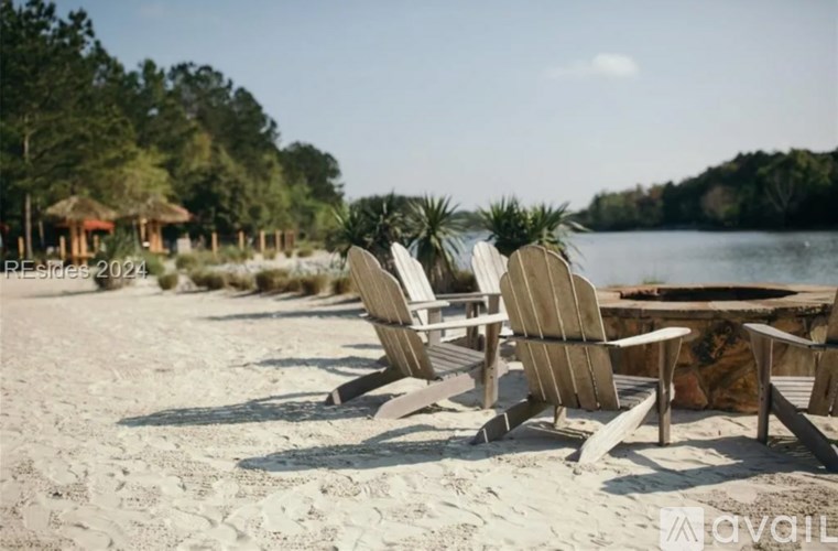 Two chairs are on a beach with a body of water in the background.