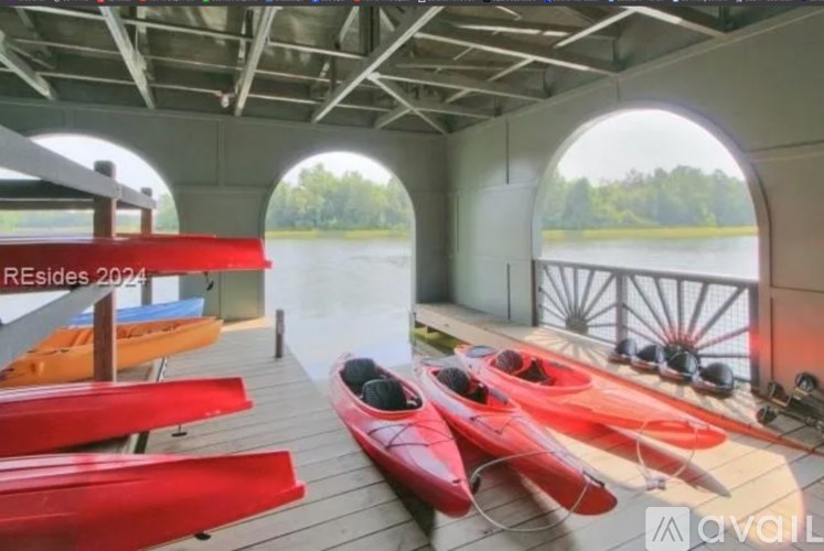 A row of red kayaks are lined up on a wooden deck.