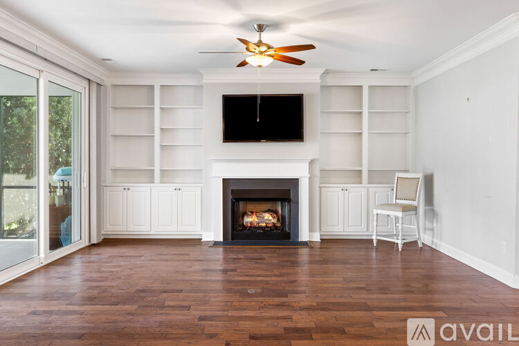 A living room with a fireplace and a television mounted above it.