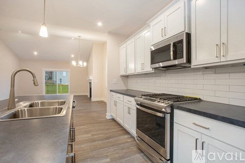A kitchen with white cabinets and a stainless steel sink and oven.