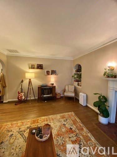 A living room with a guitar, a chair, a table, and a fireplace.