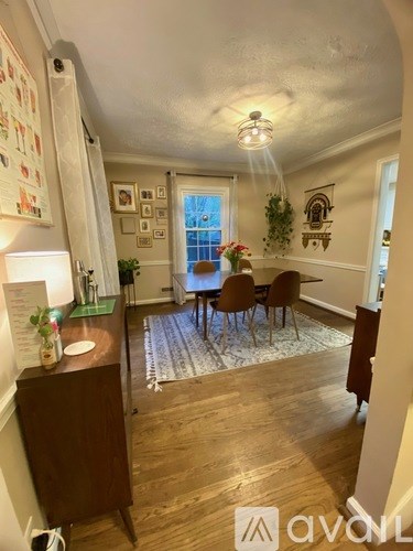 A dining room with a table set for four and a kitchen area with a sink.