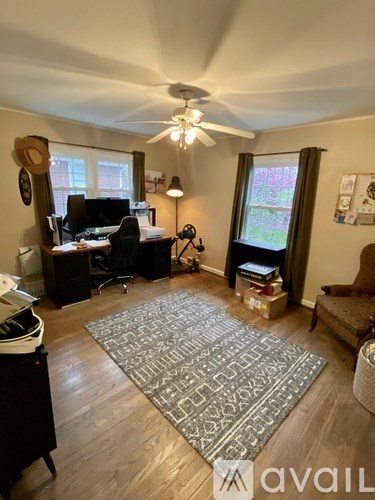 A room with a ceiling fan and a rug on the floor.