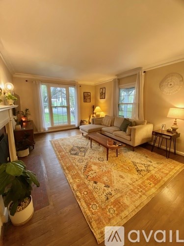A living room with a rug, a couch, a table, and a fireplace.