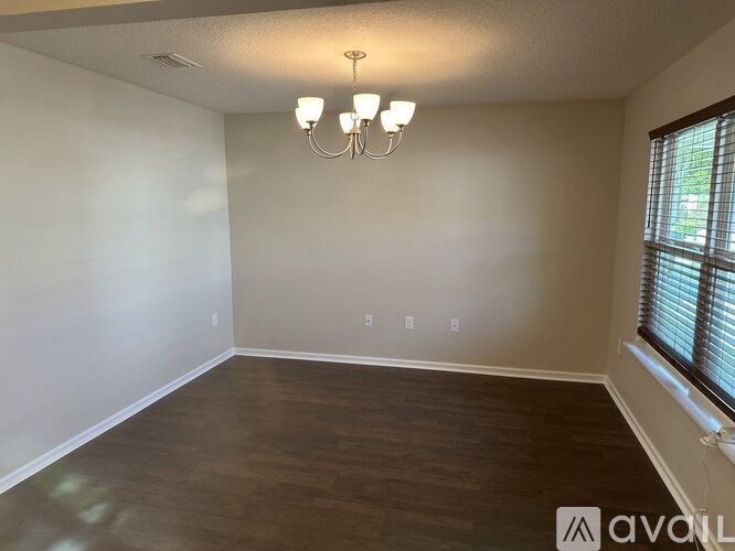 A room with wooden flooring and a chandelier.