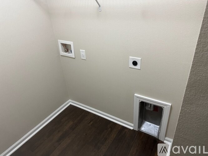 A room with a brown floor and a white wall with two switches and one socket.