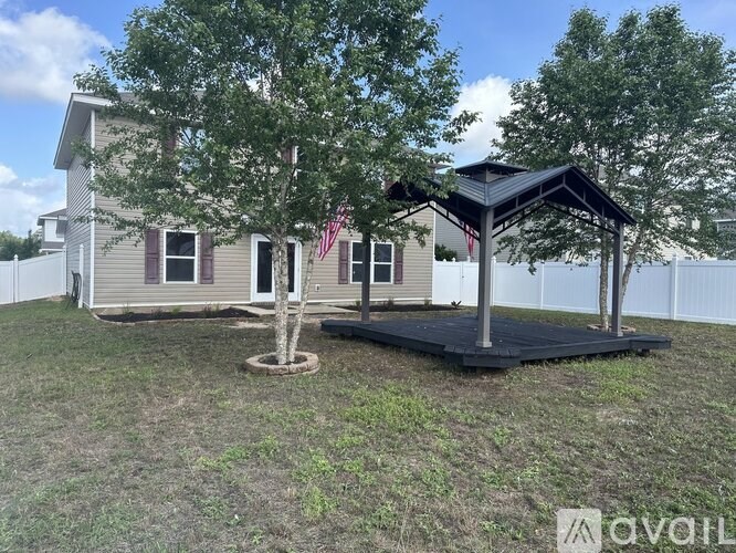 A house with a tree and a gazebo in the yard.