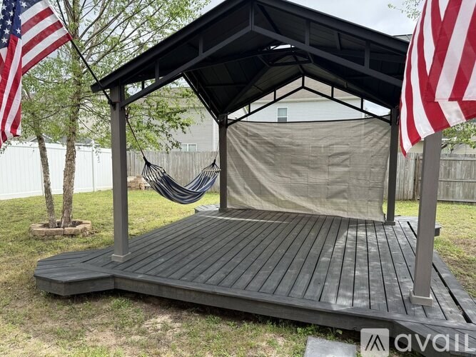 A wooden deck with a hammock and two American flags.