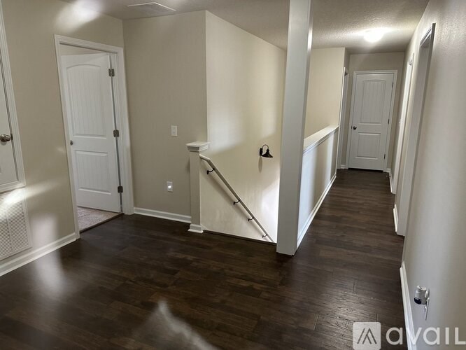 A hallway with dark wood floors and white walls.