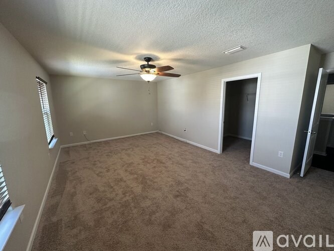 A room with a carpeted floor and a ceiling fan.