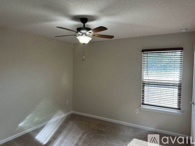 A room with a ceiling fan and a window with blinds.